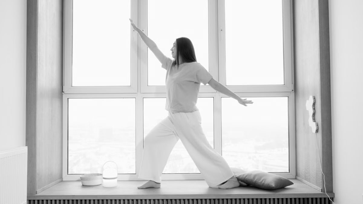 Woman practicing yoga indoors, in a stylish black and white ambiance.